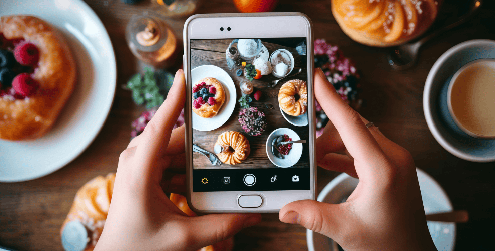 Una persona scatta una foto con uno smartphone di un tavolo da colazione colorato per creare contenuti attraenti per il marketing su Instagram.