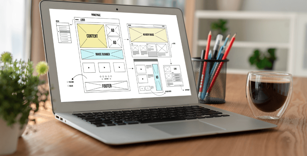 Laptop con uno schermo che mostra un mockup dettagliato di una pagina web con layout e segnaposti, simboleggiando il design di un tutorial per la risoluzione di problemi tecnici comuni come il caricamento lento delle pagine web.