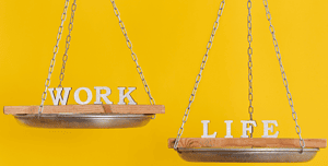 Due altalene in legno su sfondo giallo, una con la parola 'WORK' e l'altra con 'LIFE', simboleggiando l'equilibrio tra vita professionale e personale essenziale per i web designer.