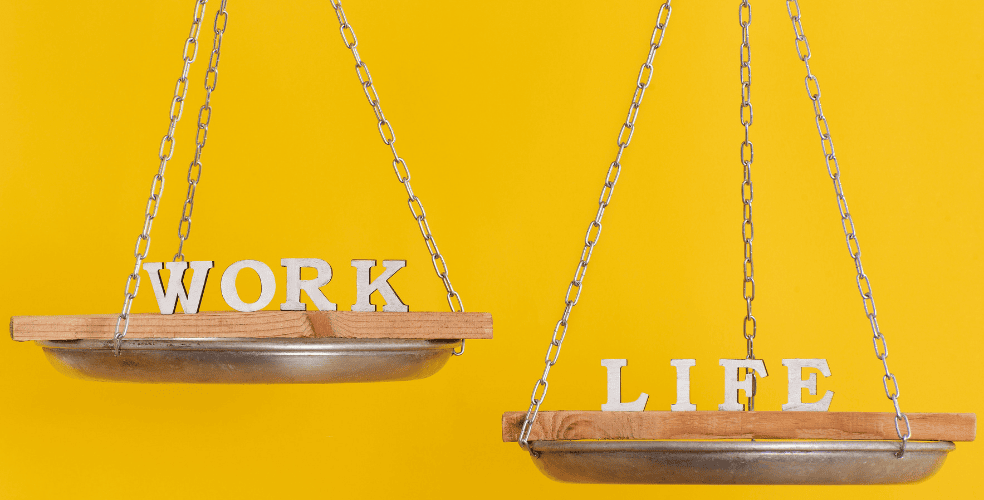 Due altalene in legno su sfondo giallo, una con la parola 'WORK' e l'altra con 'LIFE', simboleggiando l'equilibrio tra vita professionale e personale essenziale per i web designer.