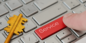 Dito che preme un tasto rosso con la parola 'Service' su una tastiera moderna in alluminio accanto a una chiave d'oro, rappresentando la progettazione attenta di una pagina di servizi su un sito web.