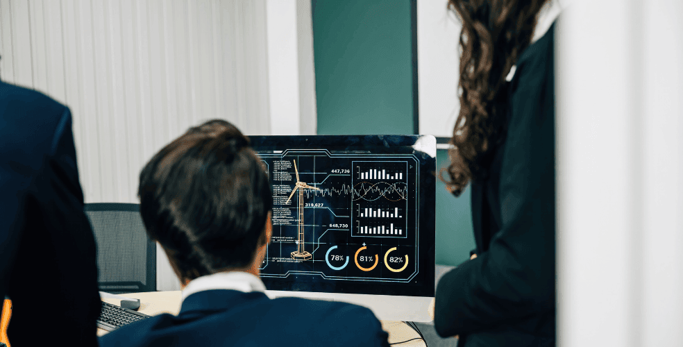 Gruppo di persone in abiti formali che osservano un monitor con grafici e dati complessi, rappresentando l'analisi e il confronto di diverse versioni di interfacce utente tramite A/B testing.