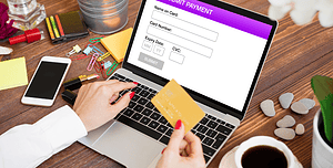 Persona che effettua un pagamento online su un laptop, inserendo i dati della carta di credito in un modulo di pagamento.