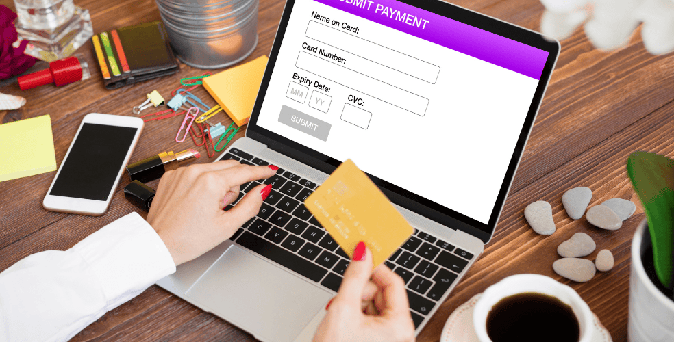 Persona che effettua un pagamento online su un laptop, inserendo i dati della carta di credito in un modulo di pagamento.