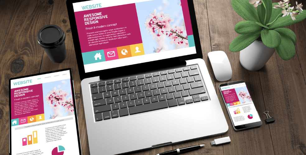 Dispositivi digitali su una scrivania mostrando un design di sito web responsivo, comprendente laptop, tablet e smartphone.