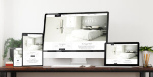 Varie schermate di un sito web per un hotel, visualizzate su diversi dispositivi (smartphone, tablet, laptop e desktop) su una scrivania, rappresentando il design responsive.