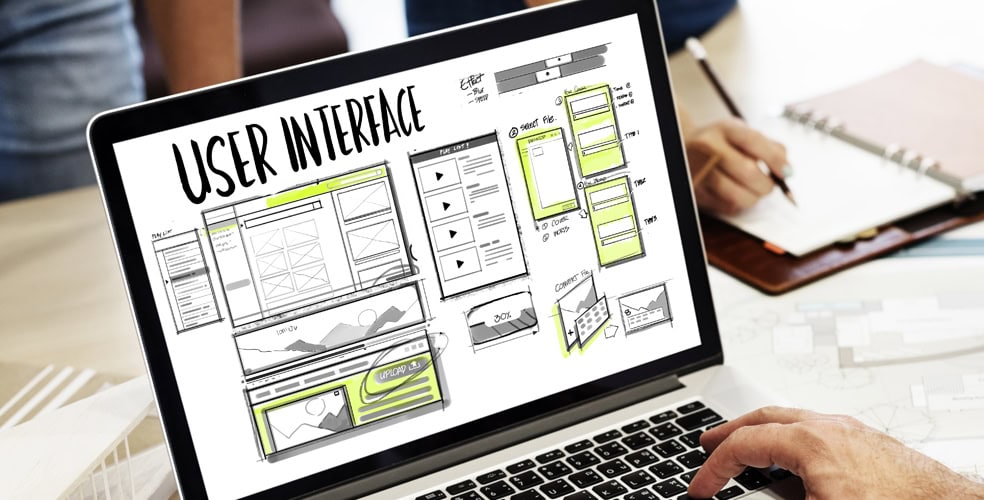 Laptop con uno schema di interfaccia utente, con persone che lavorano insieme in background, rappresentando l'importanza del back-end nel processo di creazione del sito web.