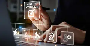 Primo piano di una mano che tocca un’interfaccia digitale trasparente con la scritta “Quality Assurance” e un segno di spunta; sotto scorrono icone semitrasparenti (stella, checklist, chiave inglese, badge di qualità, ingranaggi) davanti a un laptop, a rappresentare controllo qualità, test, conformità e miglioramento continuo in ambito digitale.