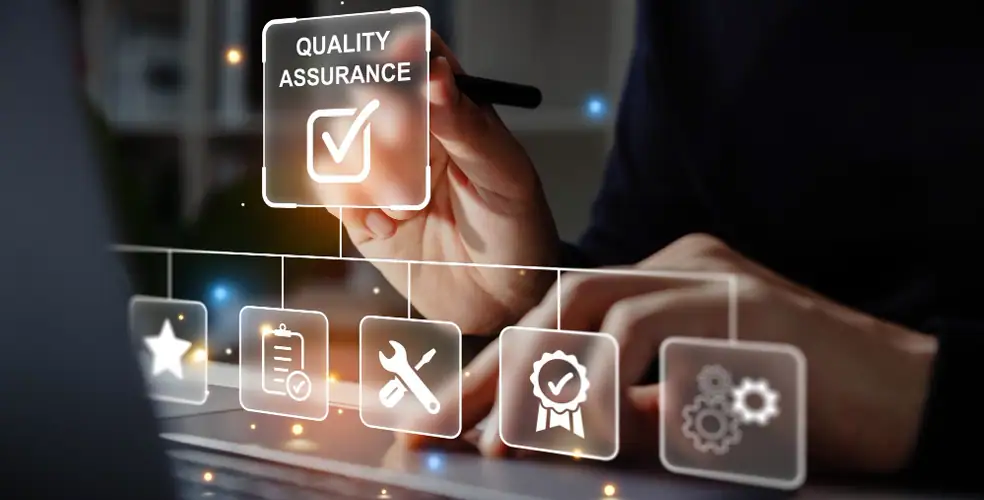 Primo piano di una mano che tocca un’interfaccia digitale trasparente con la scritta “Quality Assurance” e un segno di spunta; sotto scorrono icone semitrasparenti (stella, checklist, chiave inglese, badge di qualità, ingranaggi) davanti a un laptop, a rappresentare controllo qualità, test, conformità e miglioramento continuo in ambito digitale.